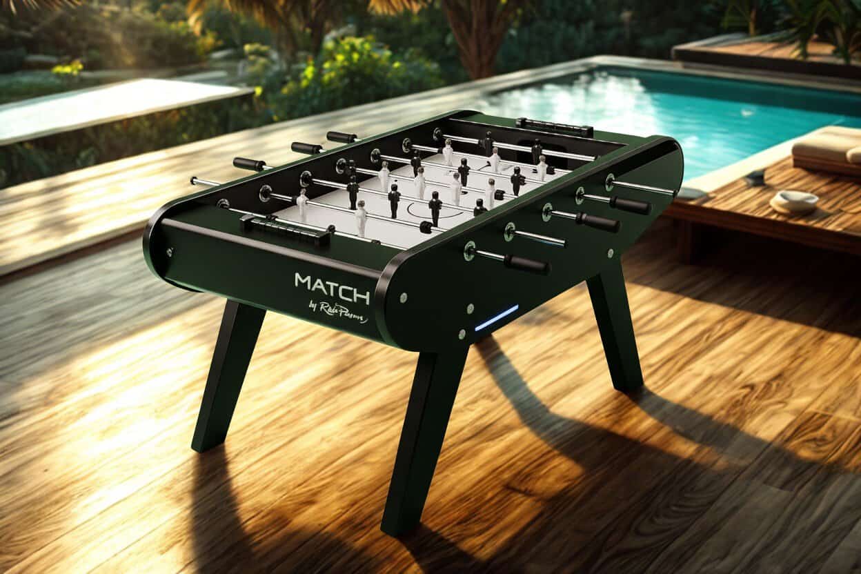 René Pierre MATCH foosball table set up on a wooden deck beside a swimming pool, with a garden behind