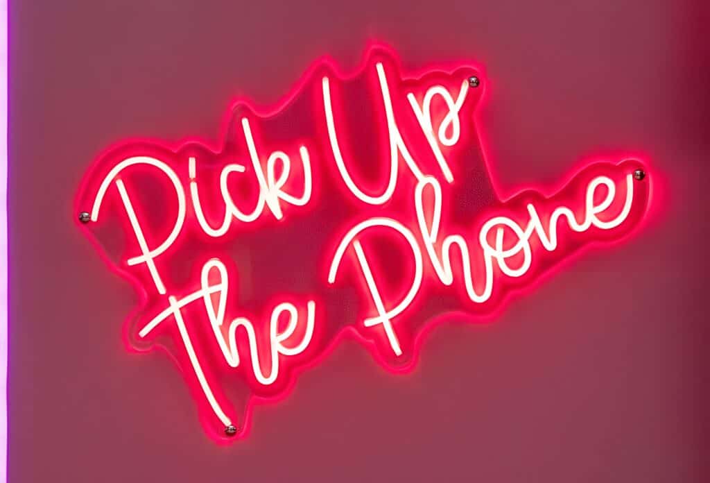 Pink “Pick Up The Phone” neon sign of an audio guest book